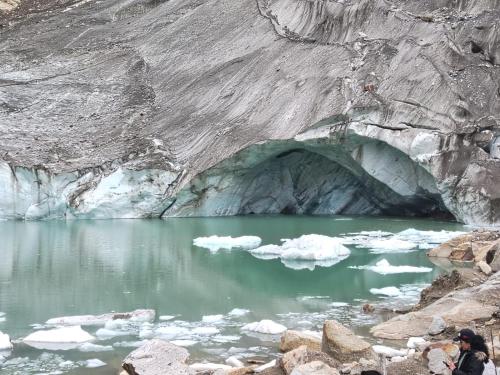 a cave in the side of a mountain next to a body of water at Tony Montaña B&B in Huaraz