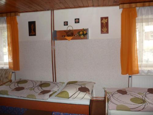 a bedroom with two beds with orange curtains at Pension Mikulka in Mikulov v Krušných Horách