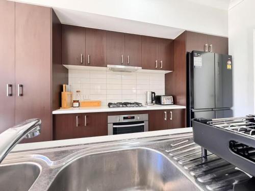 a kitchen with a sink and a stainless steel refrigerator at Blue Haven Retreat - Thornton Central 60 in Penrith