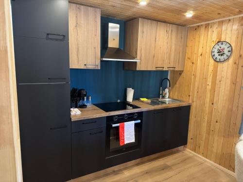 a kitchen with black appliances and a clock on the wall at Mountain Mia in Šišava