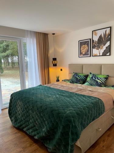 a bedroom with a large bed with a green comforter at Leśne Zacisze Kawice in Kawice