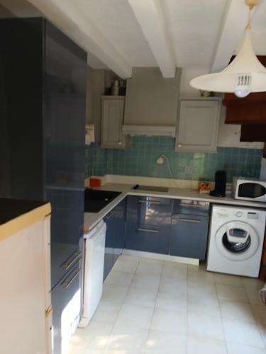 une cuisine avec des armoires bleues et une machine à laver dans l'établissement Saint-Raphaël Villa mitoyenne 10 min de la plage, à Saint-Raphaël