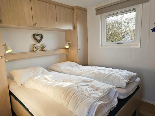 two beds in a room with a window at Chalet Olmenduin 112 SE16 in Serooskerke