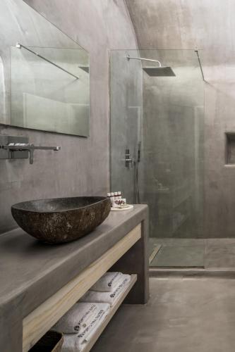 a bathroom with a stone sink and a shower at Porto Fira Suites in Fira