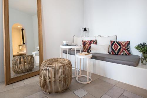 a room with a couch and a stool and a mirror at Porto Fira Suites in Fira