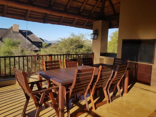 a wooden table and chairs on a deck at Zebula Golf and Wildlife Estate - Squirrel Pandemonium Pax 12 - Moi Signature Luxury villa in Mabula