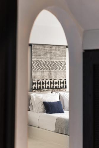 a bedroom with a bed through a mirror at Porto Fira Suites in Fira