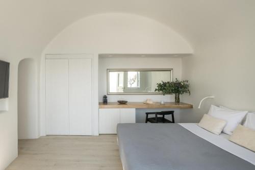 a bedroom with a bed and a desk with a mirror at Porto Fira Suites in Fira