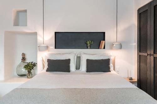 a bedroom with a large white bed with two pillows at Porto Fira Suites in Fira