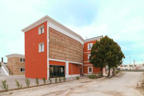 a red building with a tree in front of it at Aspio Hotel in Osimo