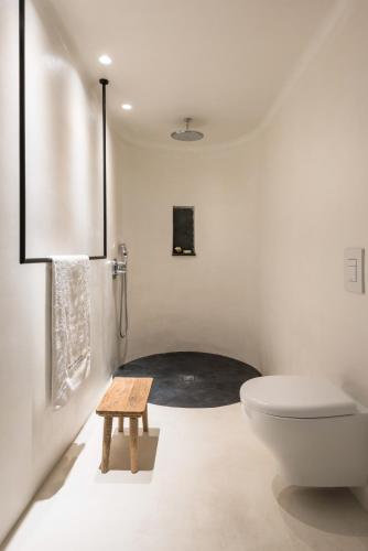 a white bathroom with a toilet and a stool at Porto Fira Suites in Fira