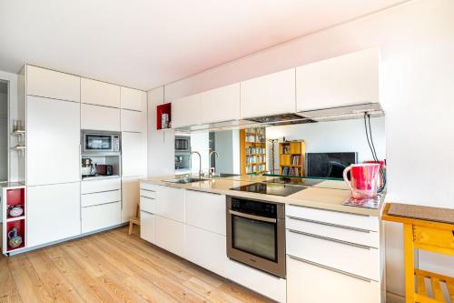 - une cuisine blanche avec parquet et placards blancs dans l'établissement GuestReady - Quaint and cute in the 15th arr, à Paris