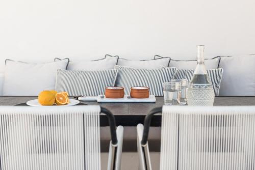 a table with a plate of oranges and a bottle of wine at Porto Fira Suites in Fira