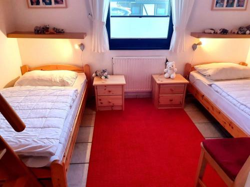 two beds in a small room with a red carpet at Ferienhaus Schöps in Burhave