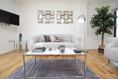 a living room with a white couch and a table at Dray Court - Hyper Central 2 Bedroom Apartment in Cardiff