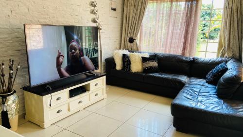 a living room with a flat screen tv on a stand at Yvee Guesthouse in Hazyview