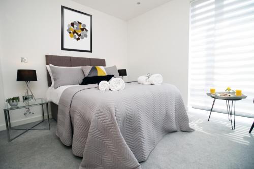 a white bedroom with a bed with towels on it at Dray Court - Hyper Central 2 Bedroom Apartment in Cardiff