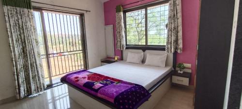 a bedroom with a bed with purple sheets and windows at ShriHari Villa in Panchgani