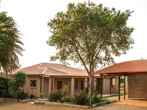 a house with a tree in front of it at Donsveertjie Gasteplaas & Venue in Heilbron