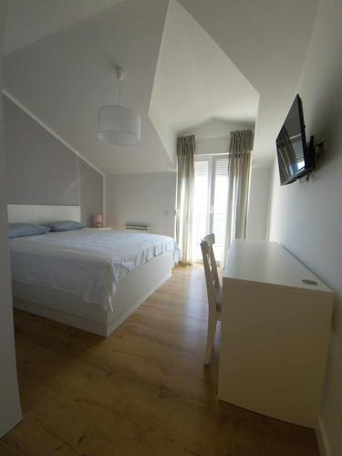 a bedroom with a bed and a desk with a television at Mare Blue in Pirovac