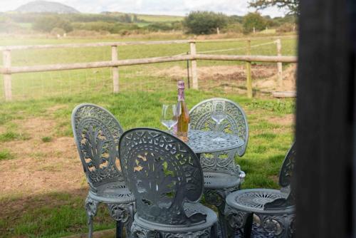 a table with four chairs and a bottle of wine at Cwt Gafr Bach in Pwllheli
