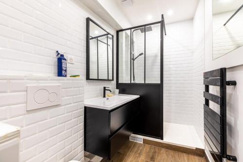 une salle de bain blanche avec un lavabo et un miroir dans l'établissement GuestReady - Modern retreat near the Eiffel Tower, à Paris