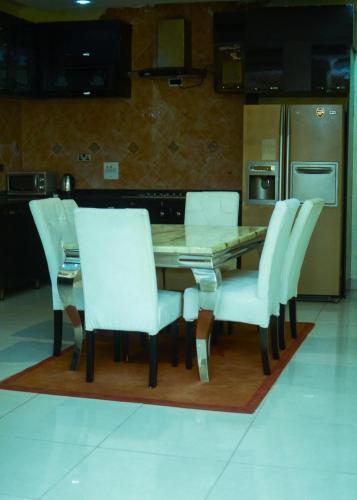 a kitchen with a wooden table and white chairs at Luxury 4 bedroom apartment in Asaba