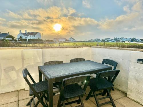 a table and chairs on a balcony with the sunset at Beach Retreat-3 Bed-Pet friendly-Central location in Trearddur