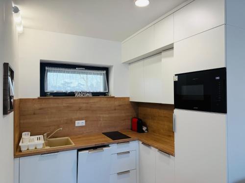 eine Küche mit weißen Schränken, einem TV und einem Kühlschrank in der Unterkunft Casa Romana 3 Siófok apartman in Siófok