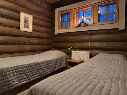 two beds in a room with wooden walls and windows at Soutajanhattu in Pyhätunturi