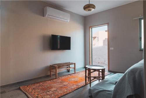 a living room with a couch and a tv on the wall at Selina Tzukim in Zuqim