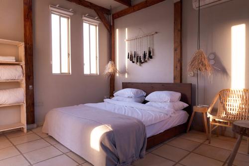 a bedroom with a large bed with white sheets and pillows at Selina Tzukim in Zuqim