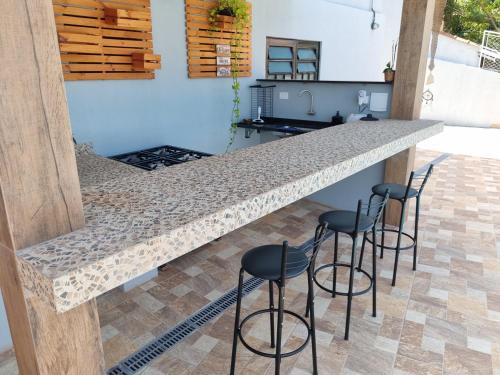 une cuisine avec un comptoir avec quatre tabourets de bar dans l'établissement Espaço Aconchegante no Centro da Cidade, à Águas de São Pedro