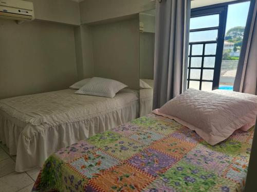 deux lits dans une chambre avec une fenêtre dans l'établissement Espaço Aconchegante no Centro da Cidade, à Águas de São Pedro