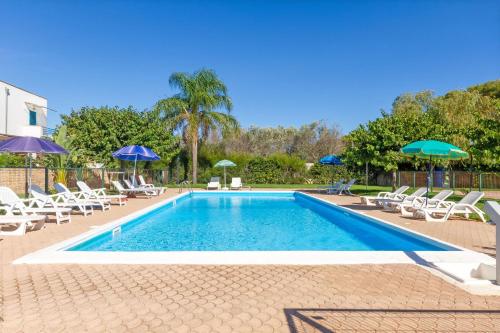 a swimming pool with chairs and umbrellas at Beach Life Apartment In Boncore in Torre Lapillo
