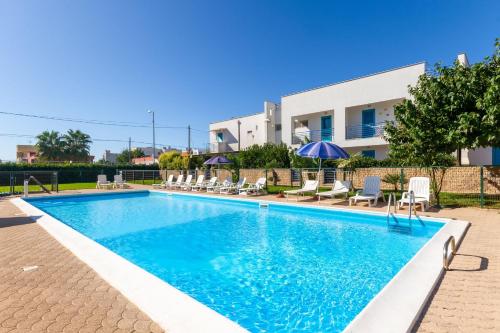 a pool with chairs and umbrellas in front of a building at Beach Life Apartment In Boncore in Torre Lapillo