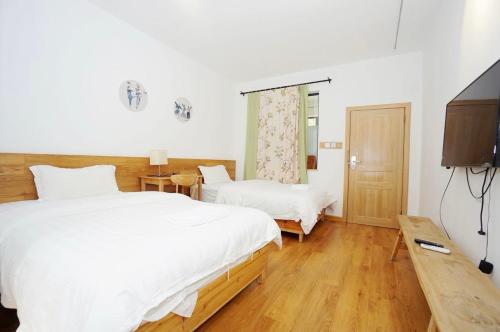 a bedroom with two beds and a flat screen tv at Junshe Youth Hostel in Guilin
