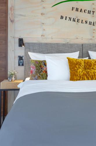 a bed with white sheets and pillows in a room at Hotel Luise & Luisenhof in Dinkelsbühl