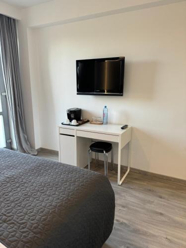 a hotel room with a desk with a television on a wall at LaHuzur Camera Dubla - Therme Balotesti & Aeroport Otopeni in Dumbrăveni