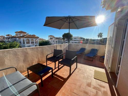 a patio with chairs and an umbrella on a balcony at Villa Jacqueline la buena vida in Playa Flamenca