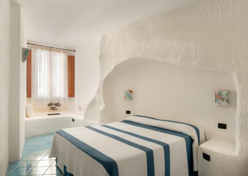 biała sypialnia z łóżkiem i wanną w obiekcie Hotel Resort & Spa Baia Caddinas w mieście Golfo Aranci