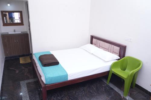 a bedroom with a bed and a green chair at Hotel SMR in Thanjāvūr