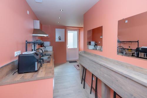 une grande cuisine avec des murs orange et un comptoir dans l'établissement Gite La Maison Du Tisserand Pa, à Les Abrets en Dauphine