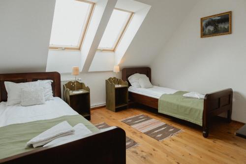 two beds in a room with two windows at Vass Panzio in Zălan