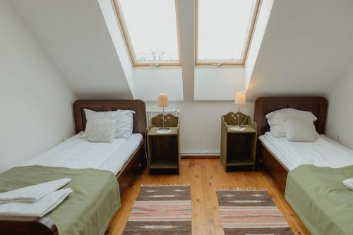 two beds in a room with two windows at Vass Panzio in Zălan