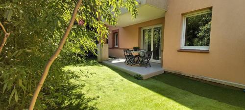 a patio of a house with a table and chairs at Les Capitouls - avec entrée autonome, clim neuve, jardin, parking privé & sa piscine ! - in Toulouse