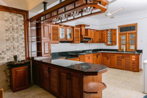 a kitchen with wooden cabinets and a black counter top at Maxxas hut in Boralesgamuwa