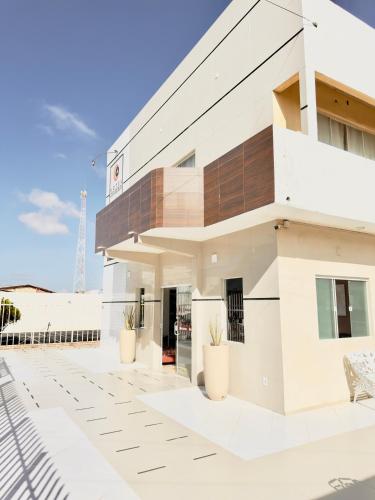 a white building with potted plants in front of it at Hotel Costa do Delta in Tutóia