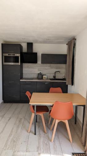 - une cuisine avec une table en bois et deux chaises orange dans l'établissement La Palombe, à Saint-Macaire