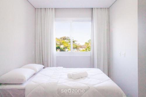 a white bed in a room with a window at Modern apartment with barbecue CRR201 in Florianópolis